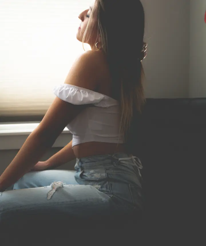 Mujer sentada junto a una ventana, pensativa