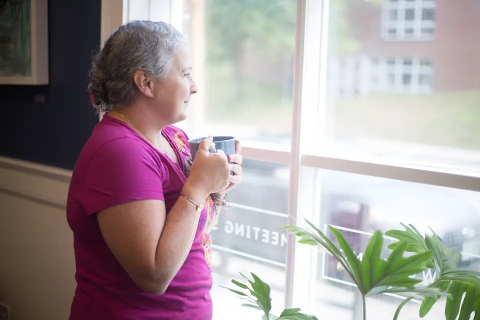 Mujer con una taza junto a la ventana